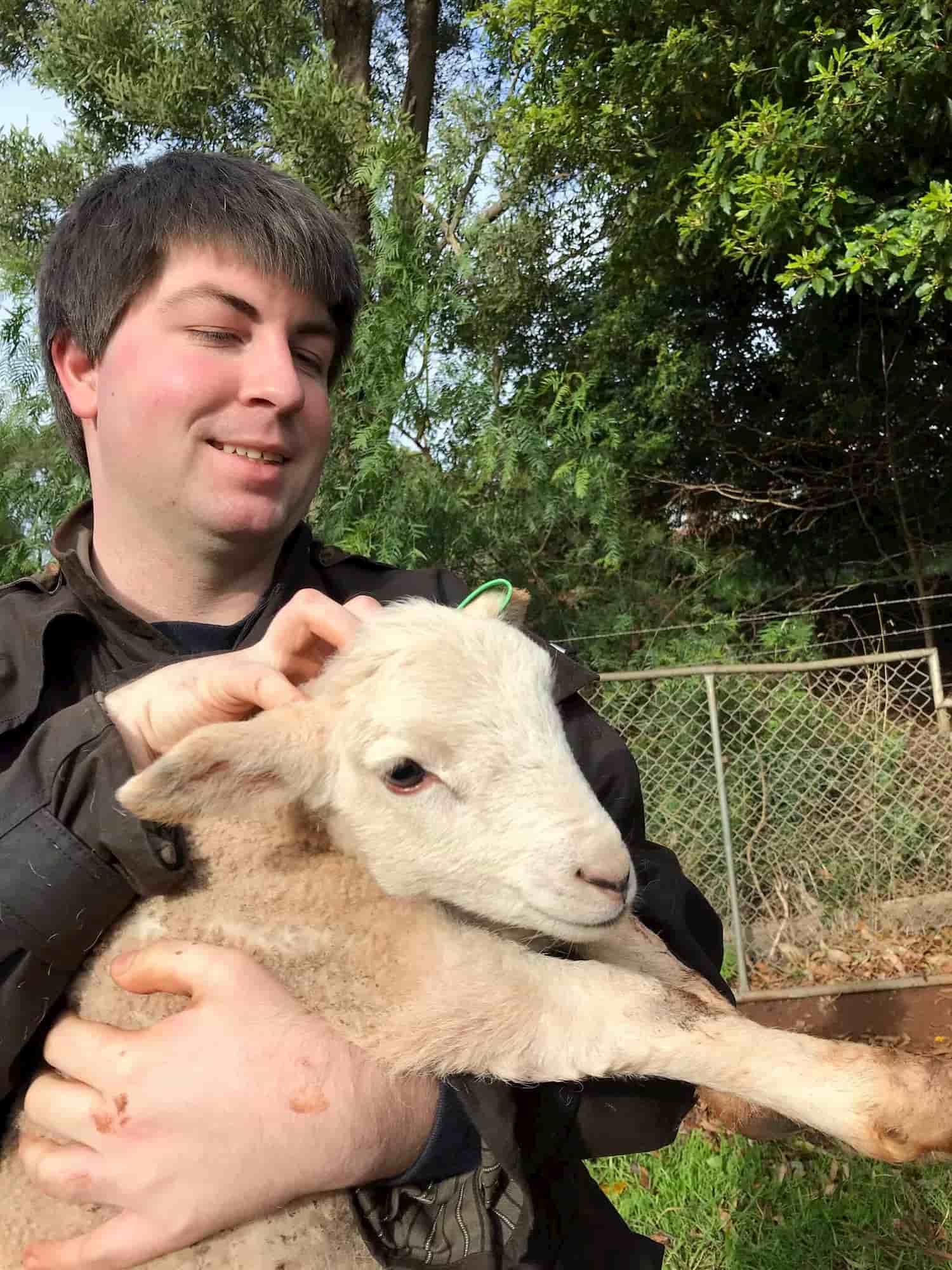 Dr Ben Dodds with pet lamb in front of a garden