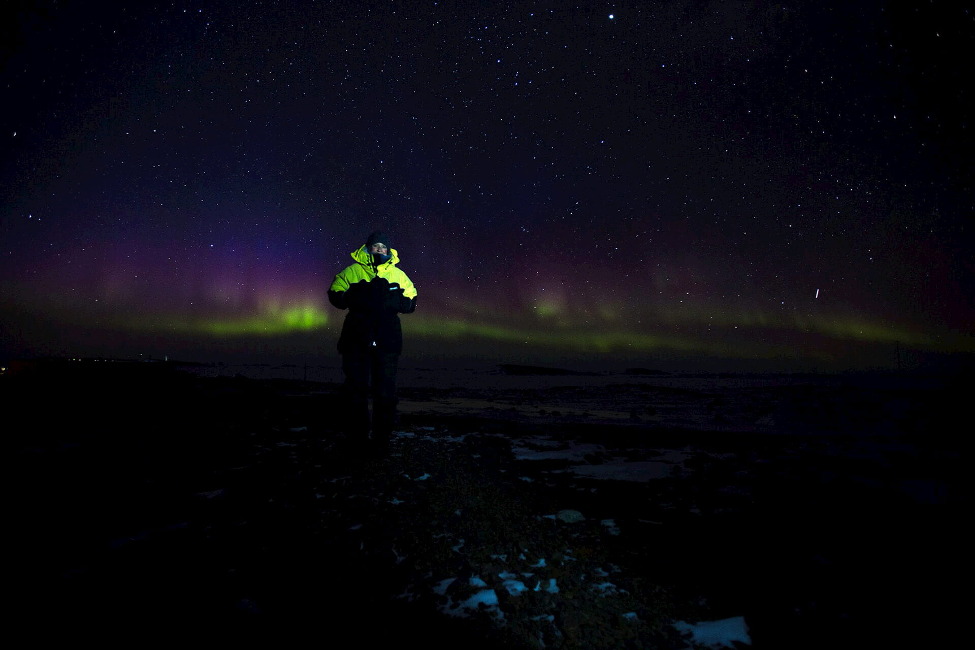 Dr Meg McKeown standing in Antarctica with Aurora Australis behind her