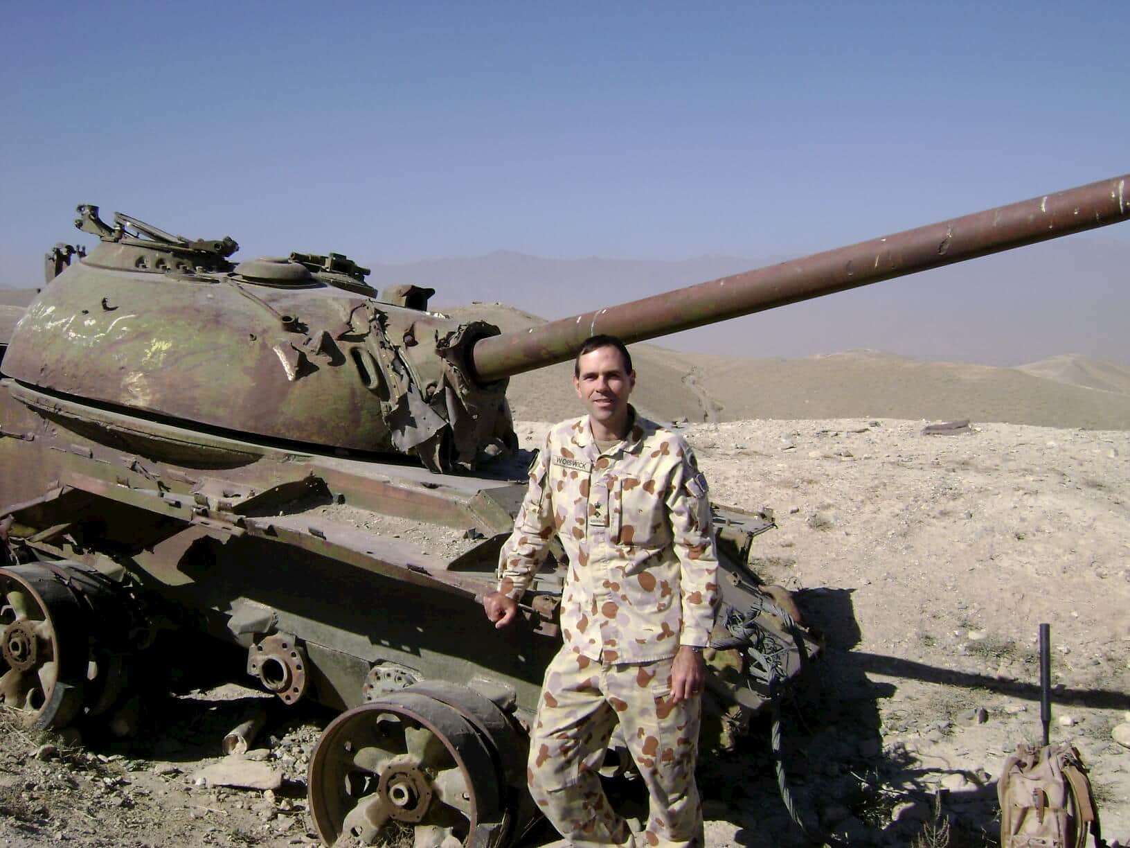 Dr Robert (Bob) Worswick standing next to destroyed Russian tank in Afghanistan